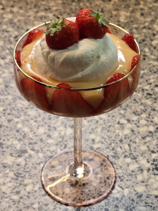 Glass dessert coupe with creamy pudding, whipped cream, and strawberries