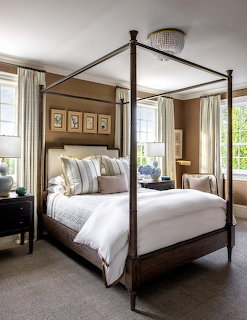 Elegant bedroom with four-poster bed, white bedding, striped pillows, and windows with curtains