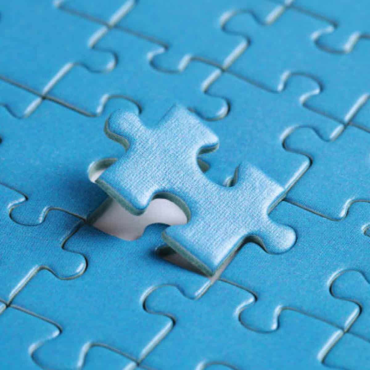 Two blue jigsaw puzzle pieces being connected together on a blue puzzle surface