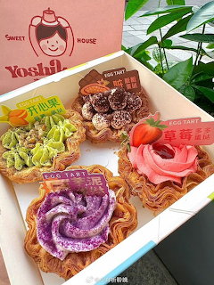 Four rectangular tarts with colorful swirled frosting and fruit toppings arranged on a white serving tray