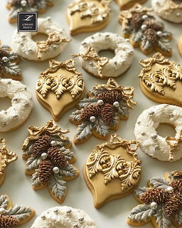 Assorted decorated Christmas cookies with festive icing, pine cones, and holiday ornaments in gold and white tones