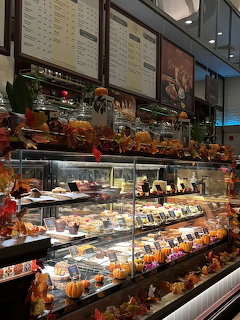 Bakery display case with desserts and pastries decorated with autumn leaves and pumpkins