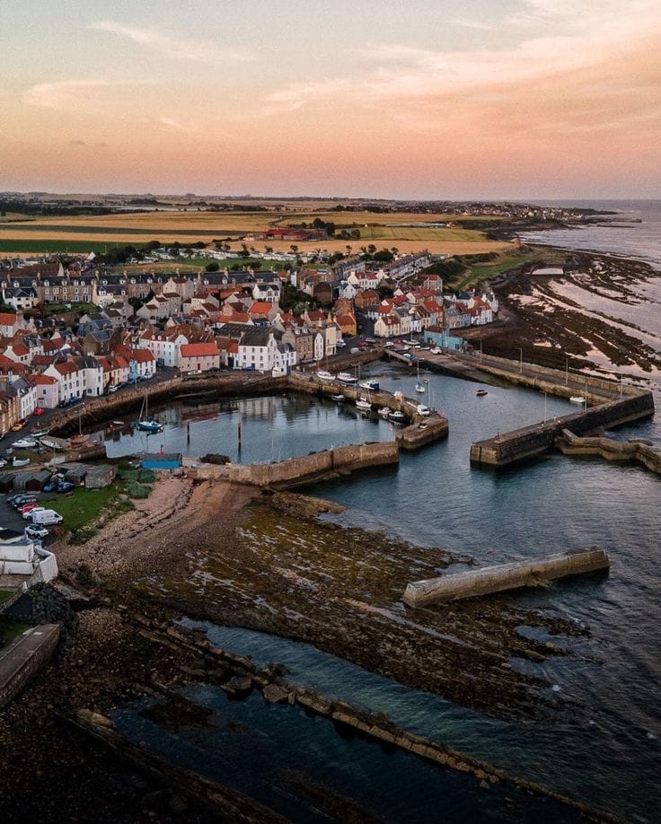 Aerial photo of a Scottish coastal village with harbour, boats, and colourful houses at sunset