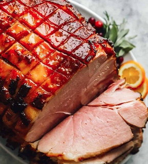 Close-up of a glazed baked ham with scored crust and sliced pieces
