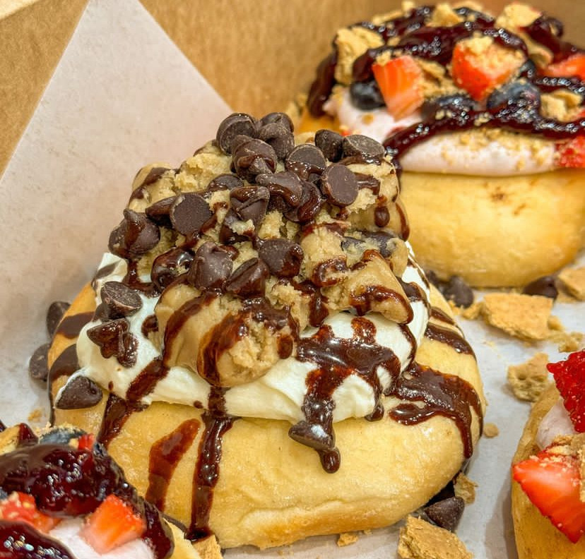 Cream-filled pastries topped with chocolate chips, chocolate drizzle, walnuts, and strawberries