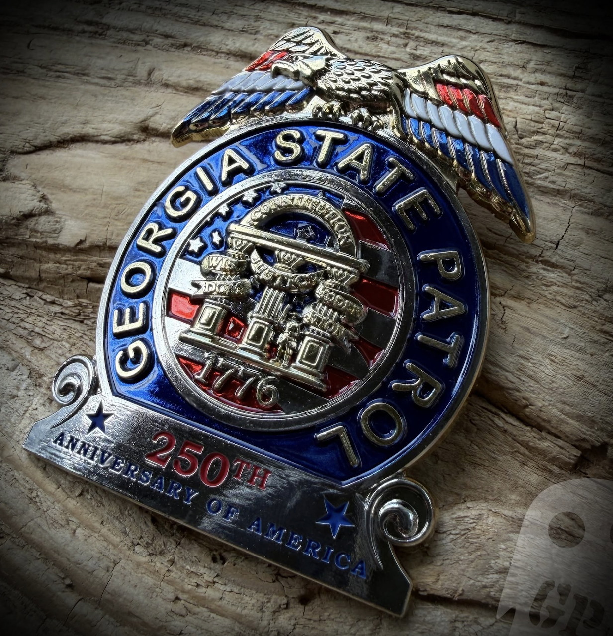 Georgia State Patrol anniversary badge resting on a weathered wooden surface