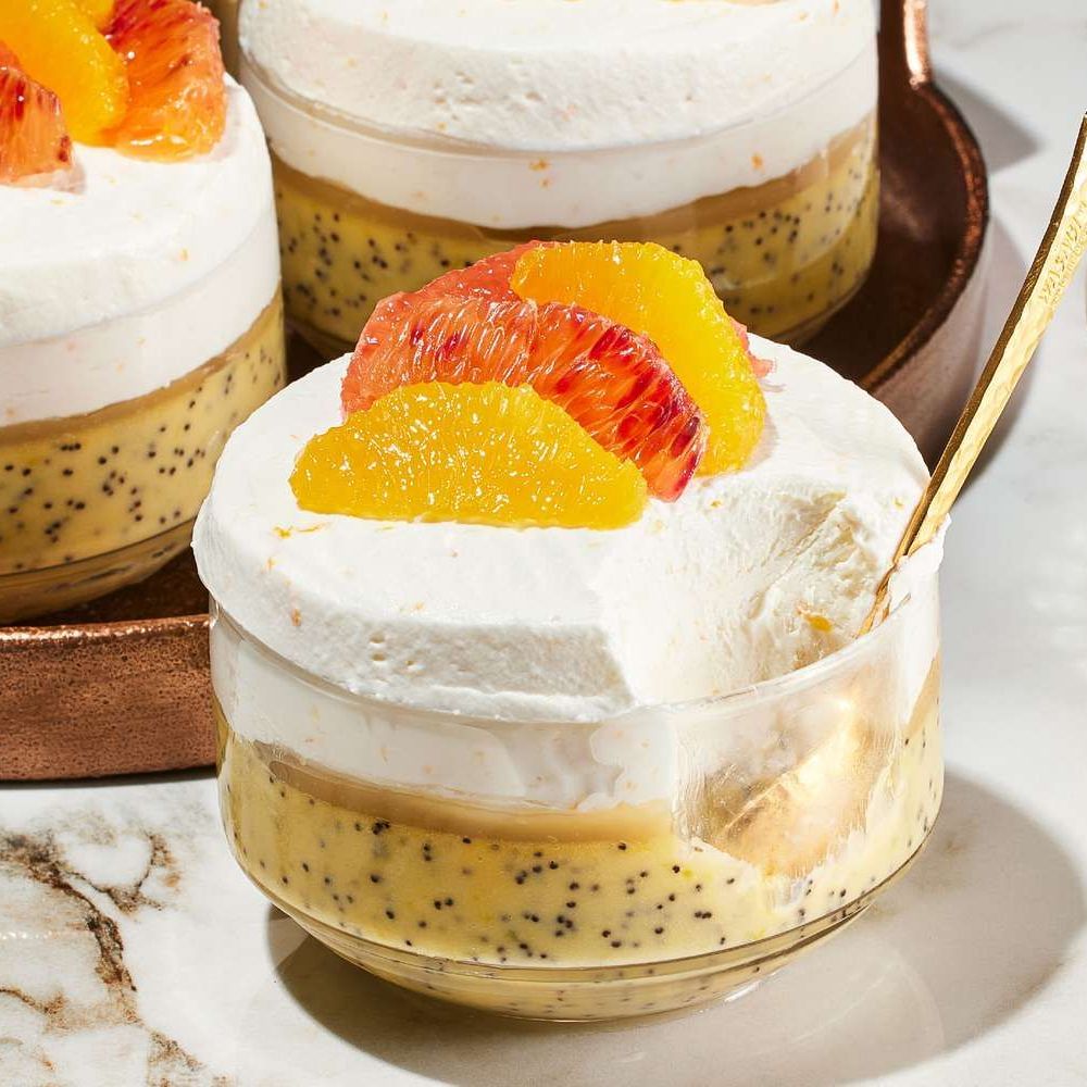 Layered citrus cream dessert in glass cups topped with whipped cream and orange slices