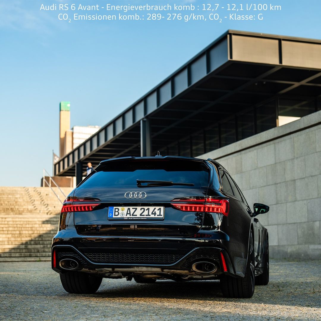 Rear view of a black Audi RS6 Avant parked beside a modern building