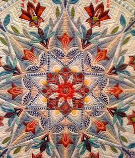 Ornate quilted star pattern with floral elements and intricate stitching in warm and cool colors