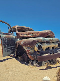 Rusted abandoned 1952 Ford truck in a desert setting under clear blue sky