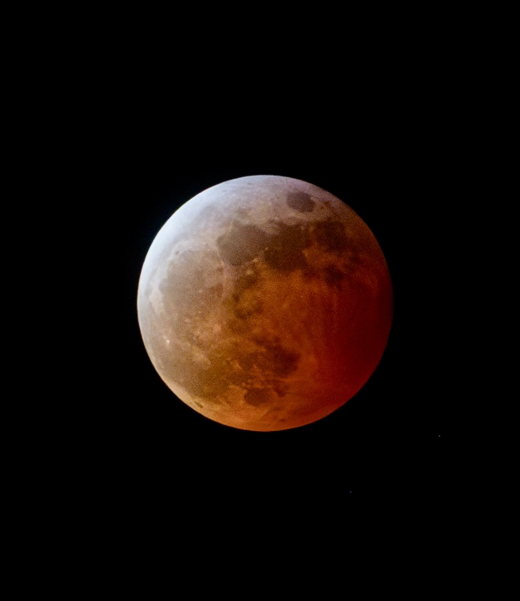 Close-up of a reddish full moon against a black night sky