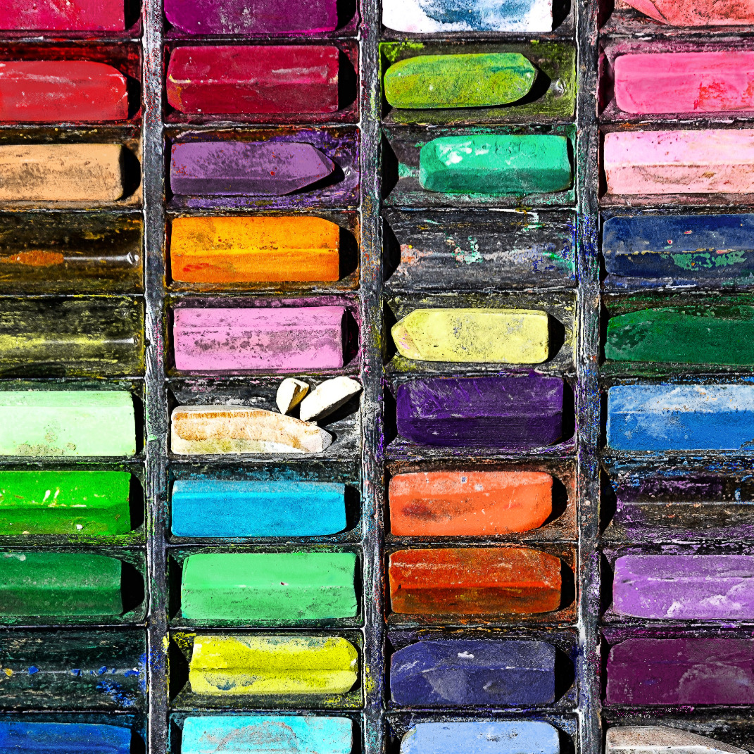 Rows of colorful artist chalk pastels organized in wooden compartments