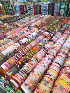 Colorful woven bracelets arranged in rows at beach market jewelry display