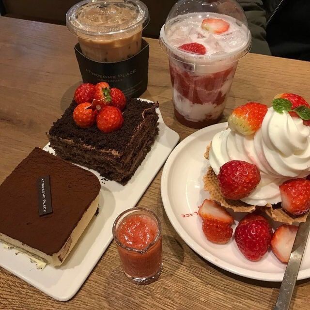Cafe table with chocolate cake, tiramisu, strawberry desserts, and iced coffee beverages