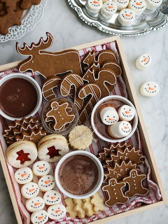 Overhead view of Christmas cookies and hot chocolate on wooden board with snowman and gingerbread shapes