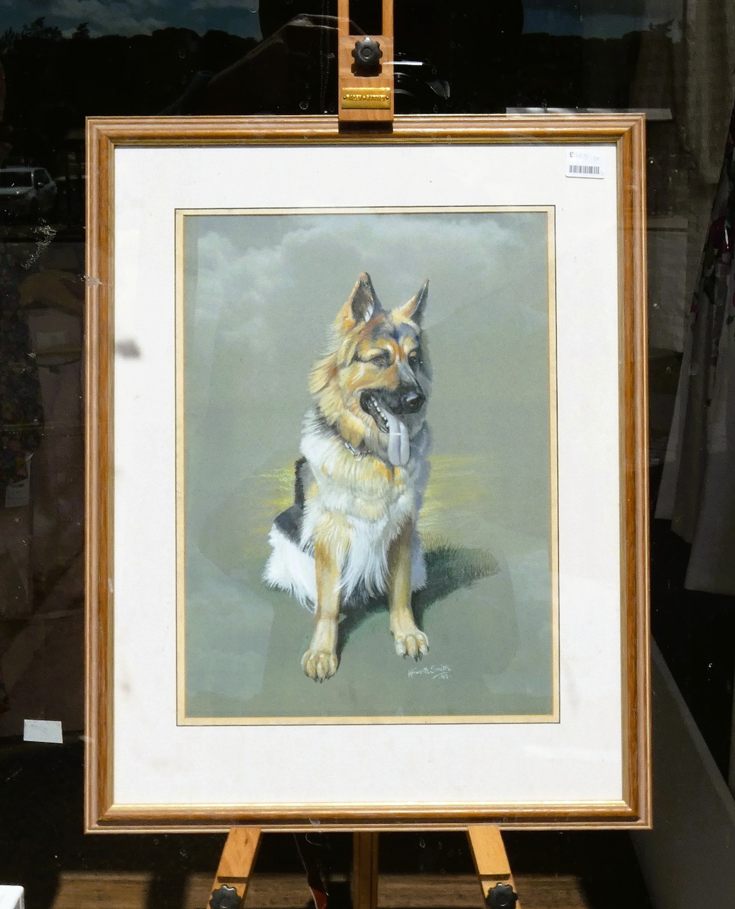 Framed painting of a seated German Shepherd on an easel