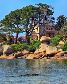 Stone house surrounded by pine trees and pink granite boulders on the coast of Ploumanac'h, Brittany