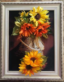 Framed artwork of yellow and orange sunflowers in a woven basket with dark background