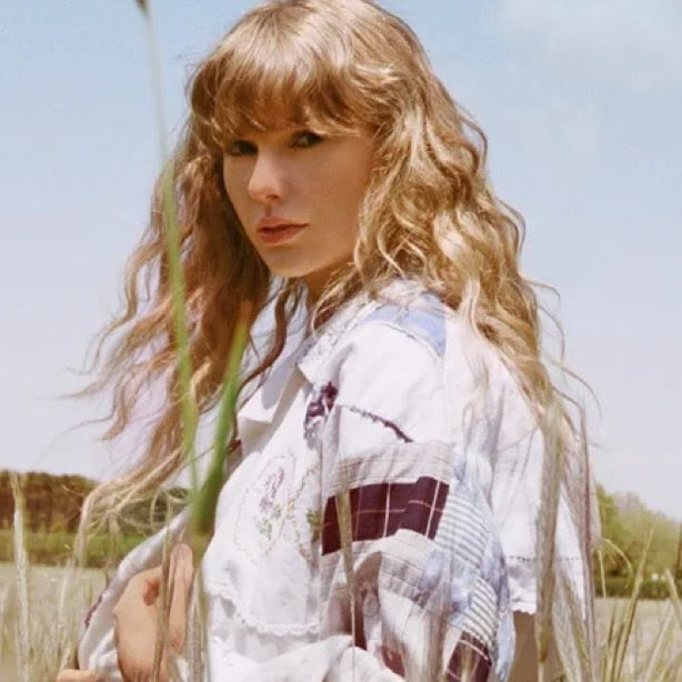 Blonde woman with wavy hair in a white shirt standing in a grassy field