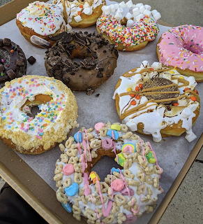 Various decorated donuts with sprinkles and frosting on a tray
