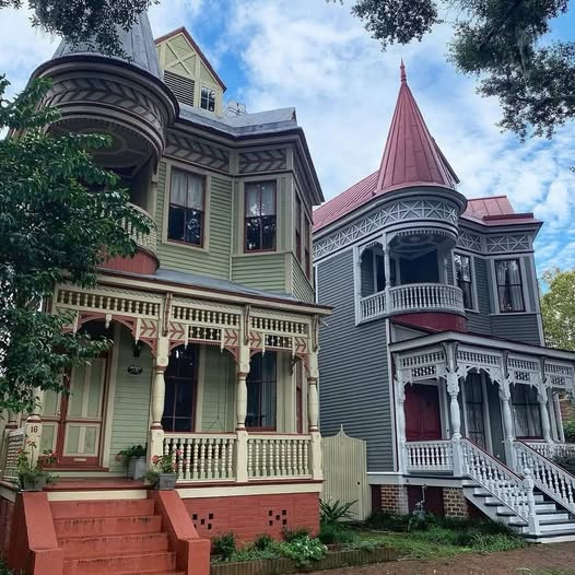 Two adjacent Victorian houses with ornate details, one green and one gray with a pink turet, in Savannah GA