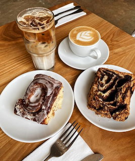Overhead view of iced coffee, latte with art, cinnamon roll and babka on a wooden table
