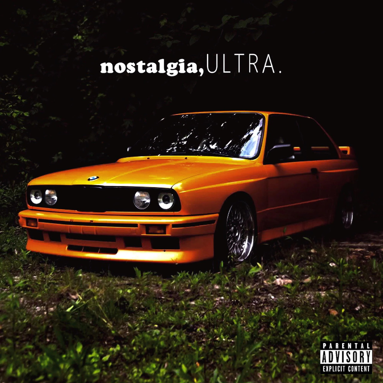 Orange BMW E30 coupe parked on grass with Nostalgia Ultra text overlay above