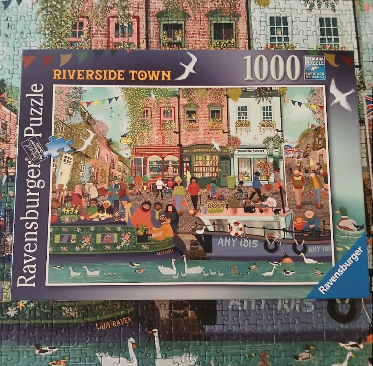 Puzzle box showing a colorful illustrated riverside town scene with boats, buildings, and people