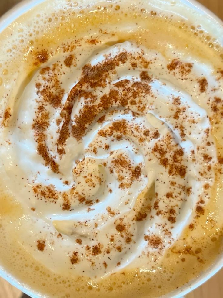 Overhead view of pumpkin spice latte with whipped cream swirl and cinnamon topping