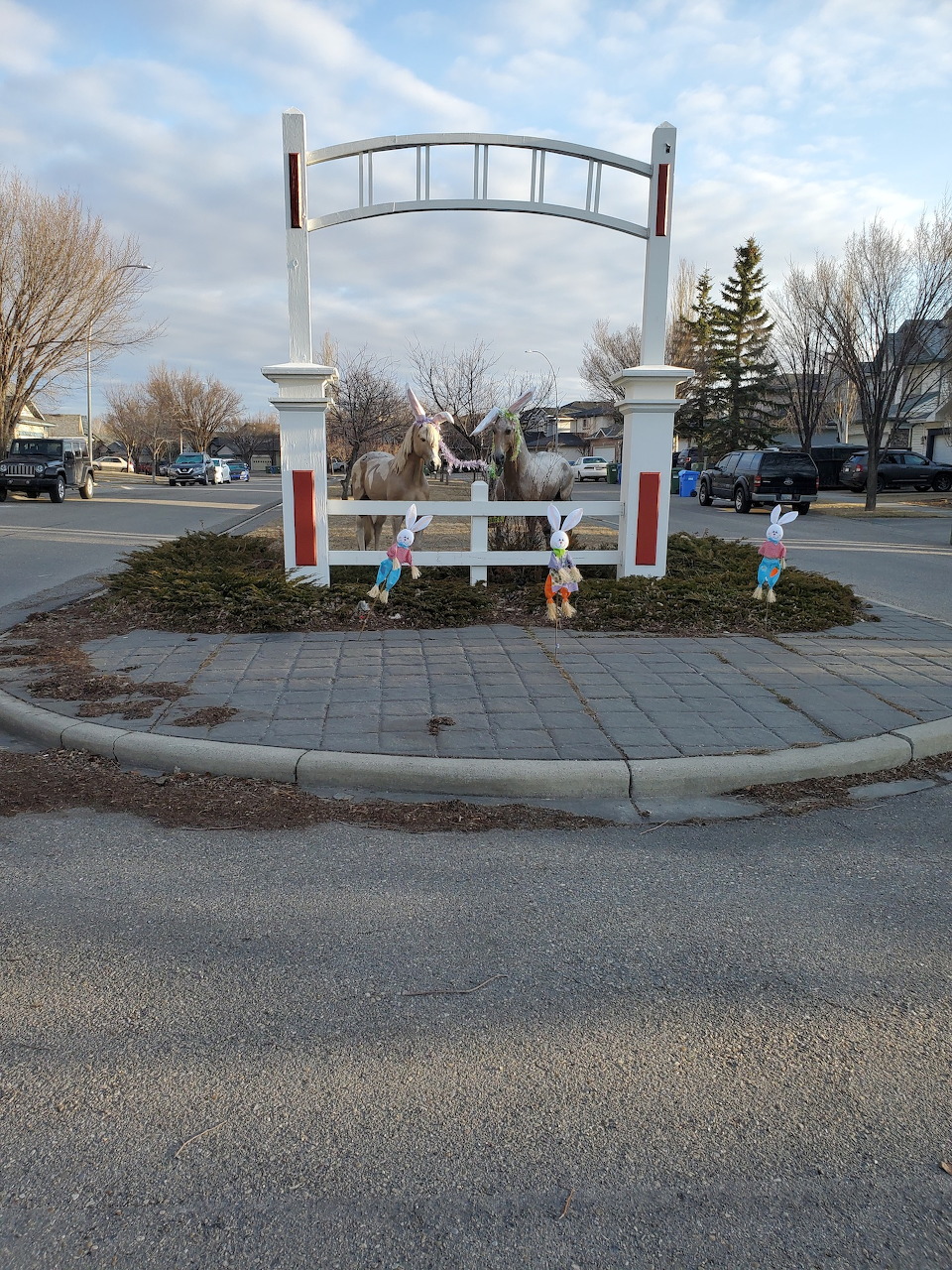 Town roundabout with white arch sign and Easter decorations including a large bunny and colorful figurines