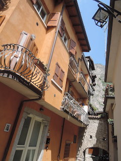Orange buildings with wrought iron balconies in a narrow Italian alley with a street lantern