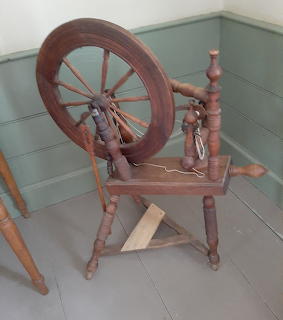 Antique wooden spinning wheel with large wheel and decorative spindles on tiled floor