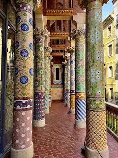 Courtyard with colorful mosaic columns and patterned tiles in various designs surrounding a central balcony