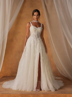 Bride in white lace wedding dress with high slit and train, standing between white curtains