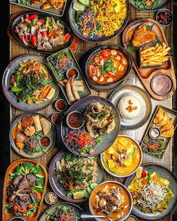 Top-down view of a table filled with assorted dishes, including noodles, soup, fries, meat, and vegetables