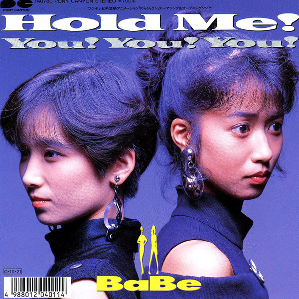 Two young women in dark clothing posed against a purple studio background