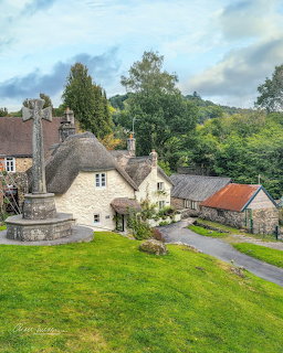 Aerial view of traditional stone cottages with thatched roofs in Lustleigh village, Devon, with green fields and hills
