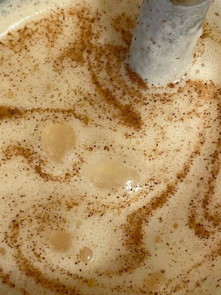 Close-up of frothy chai latte foam dusted with cinnamon