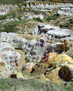 Colorful eroded canyon with white, yellow and orange rock layers and green grass