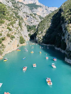 Aerial view of boats on turquoise water between tall white limestone cliffs in a narrow canyon