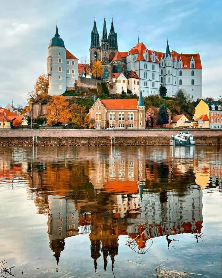 Historic castle and village on a lakeshore with a clear reflection in calm water