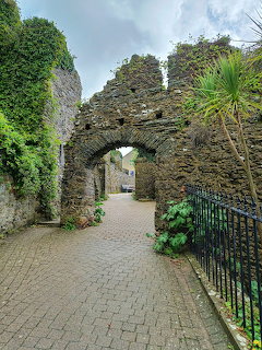 Stone medieval archway in Tenby town walls, Wales, with cobbled path and green vegetation