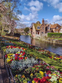 Canterbury river with vibrant flower gardens and historic buildings under blue sky