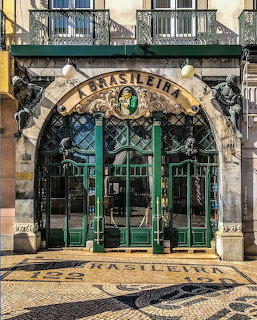 Ornate Art Nouveau facade of A Brasileira café in Lisbon with green ironwork arch and sculptural details