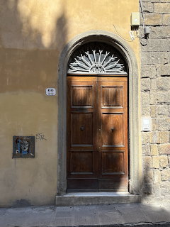 Arched wooden door with ornate fanlight transom in a yellow stucco Italian building facade