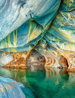 Vibrant blue and gold striped marble cave walls reflected in turquoise water