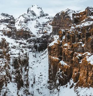 Snow-covered mountain cliffs with exposed brown rocky faces in winter