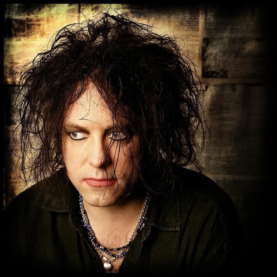 Portrait of Robert Smith with tousled black hair, pale makeup, and a dark shirt
