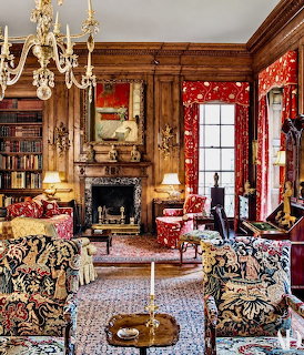 Ornate Victorian living room with floral sofas, wood paneling, chandelier, and fireplace