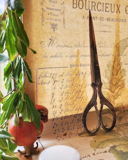 Vintage scissors on old handwritten letters with a pomegranate and green leaves